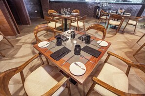 A dining area with wooden tables and chairs, each set with plates, cutlery, and glasses. - Royalton Hideaway Negril (Negril)