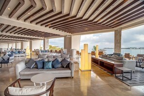 A spacious lounge area with a high ceiling, large windows, and a view of the sea. - Royalton Hideaway Negril (Negril)