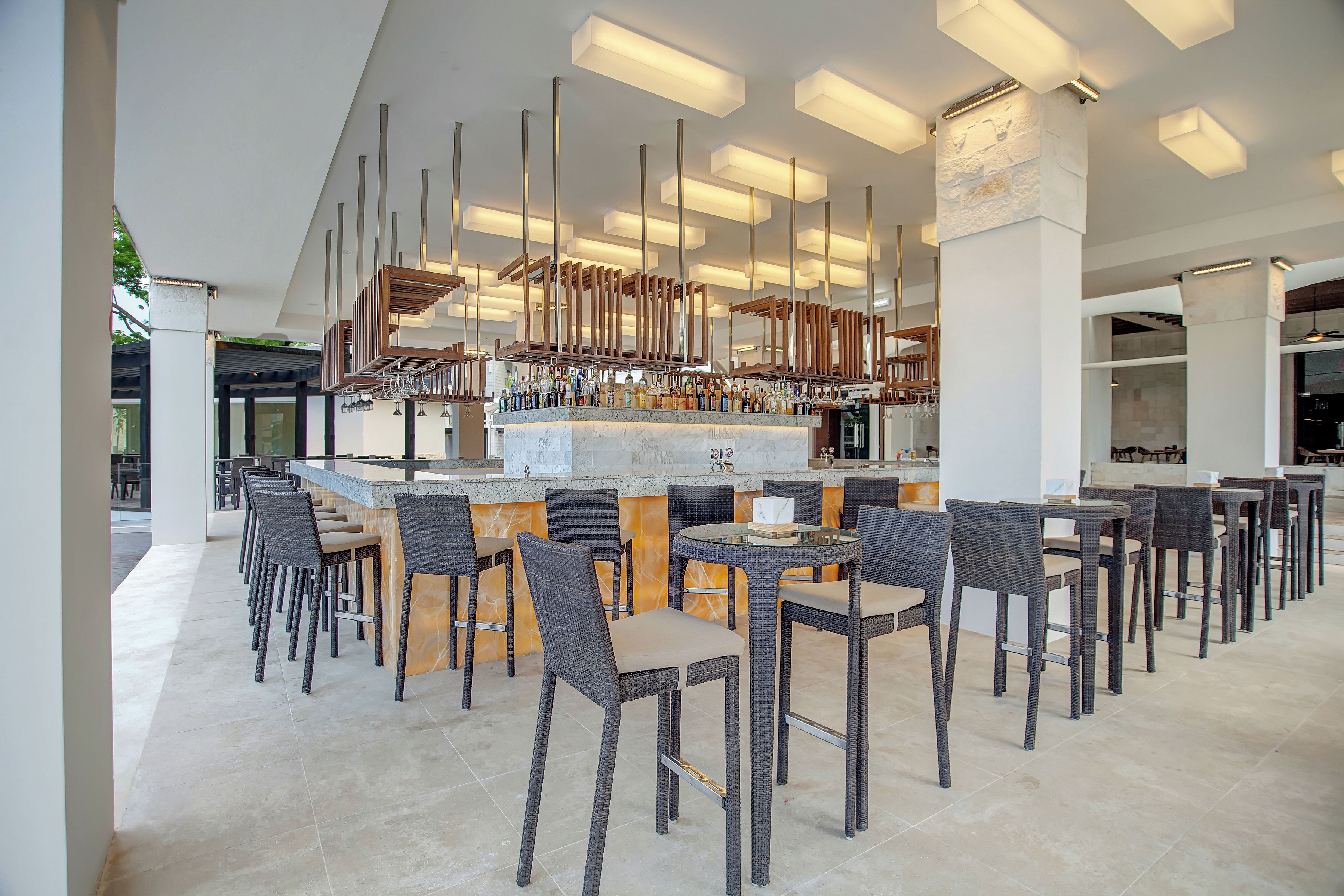 A modern bar area with high ceilings, a central bar counter, and multiple seating arrangements.