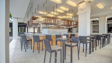 A modern bar area with high ceilings, a central bar counter, and multiple seating arrangements.