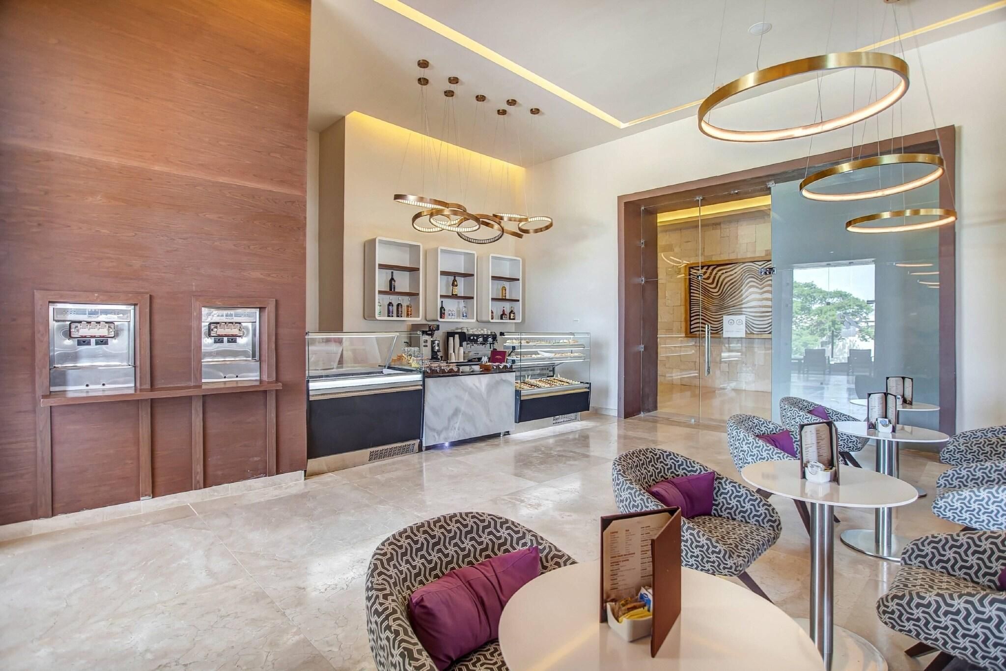 A modern hotel lobby with a reception desk, seating area, and a bar.