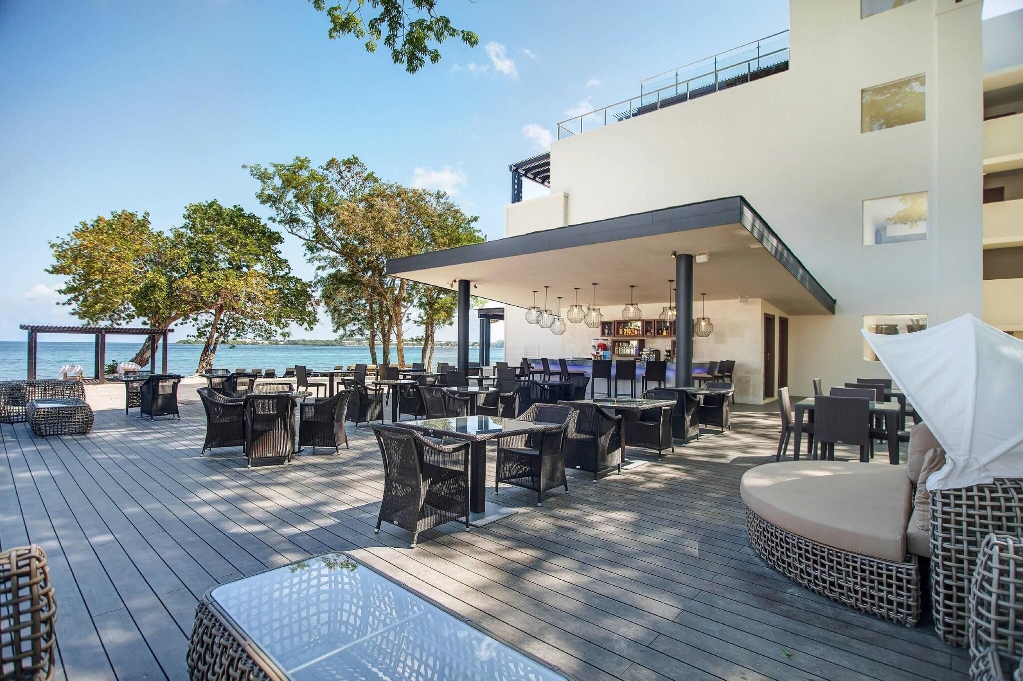 A deck with outdoor seating, a pool, and a view of the sea.