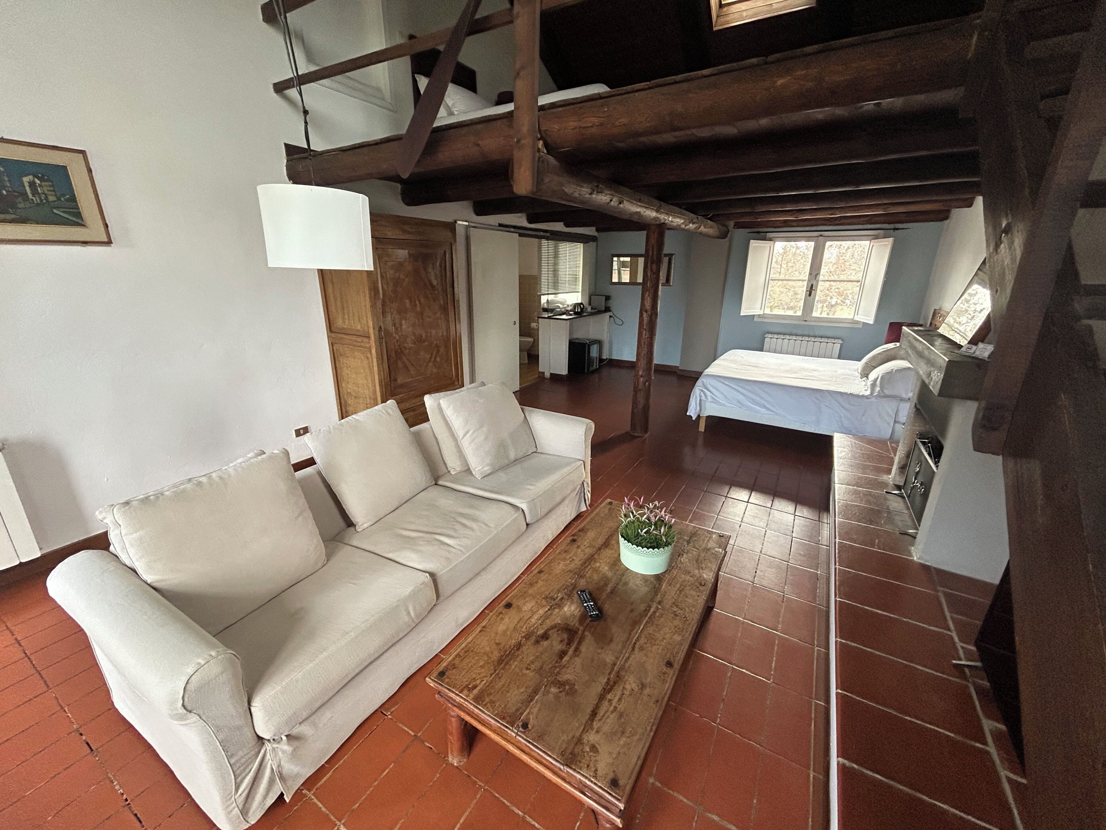A cozy living room with a sofa, a wooden coffee table, and a bed in the background.