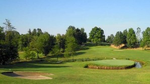 A golf course with sand bunkers, trees, and a pond.