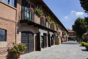 A brick building with multiple balconies, stone-paved ground, and potted plants.