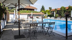 A poolside area with lounge chairs, umbrellas, and a pool.
