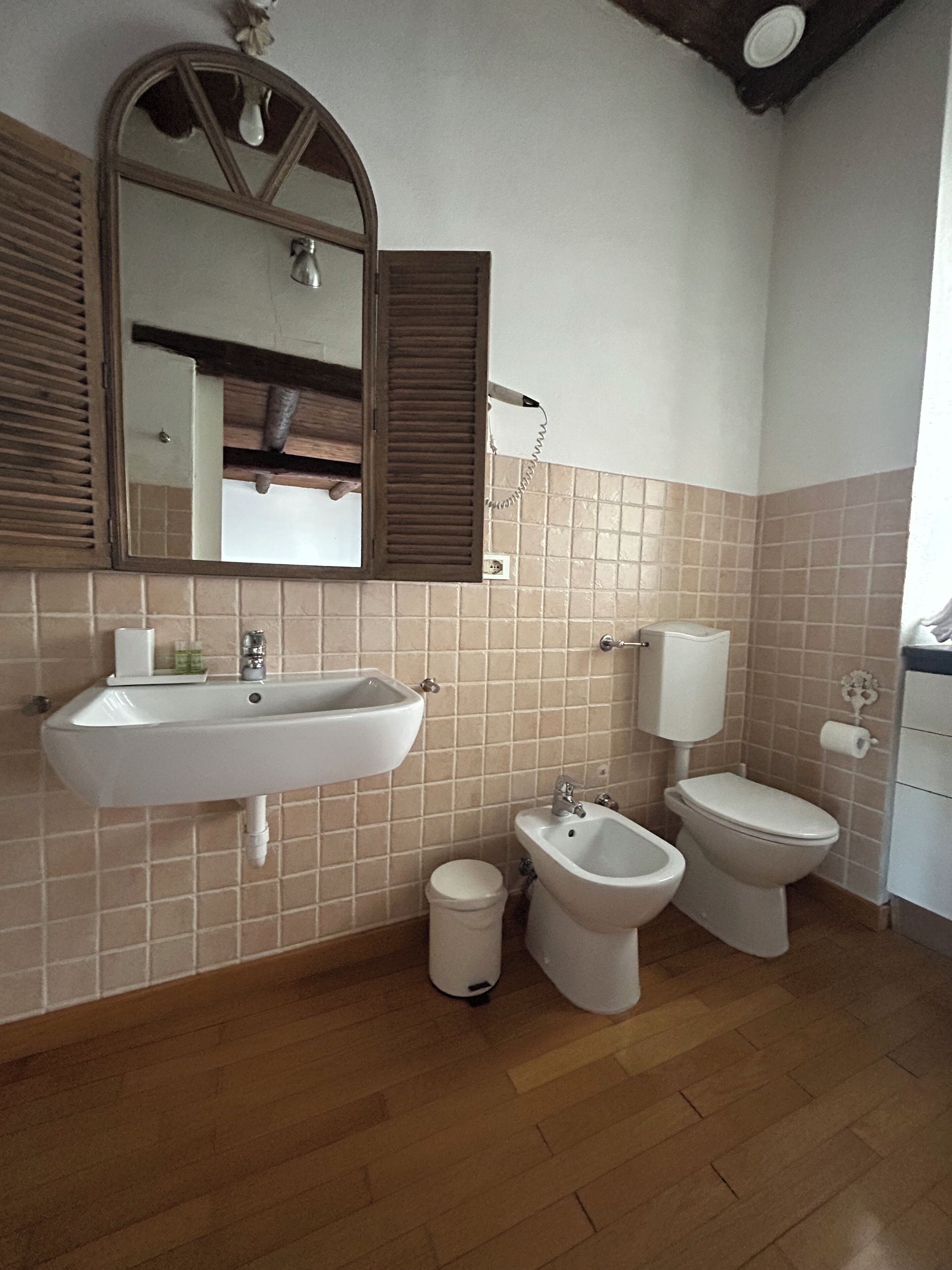 A bathroom with a sink, bidet, toilet, and a mirror with a wooden frame.