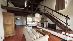 A spacious living area with a sofa, a fireplace, a television, and a staircase.