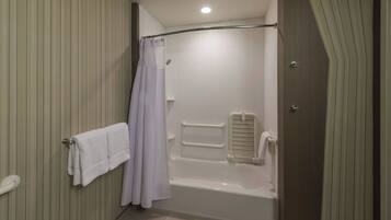 A bathroom with a bathtub, a shower curtain, a towel rack, and a handrail.
