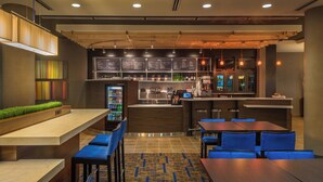 Un espace bar moderne doté d’un comptoir, de sièges et d’un tableau affichant le menu.