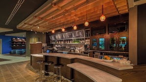 Un espace bar moderne doté d’un comptoir incurvé, de tabourets de bar et de luminaires suspendus.