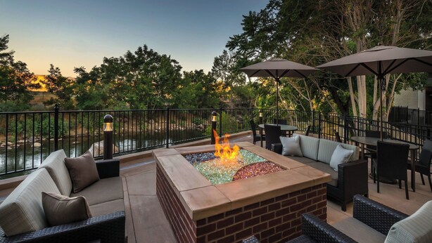 Une terrasse extérieure dotée d’un foyer, de sièges et de parasols.