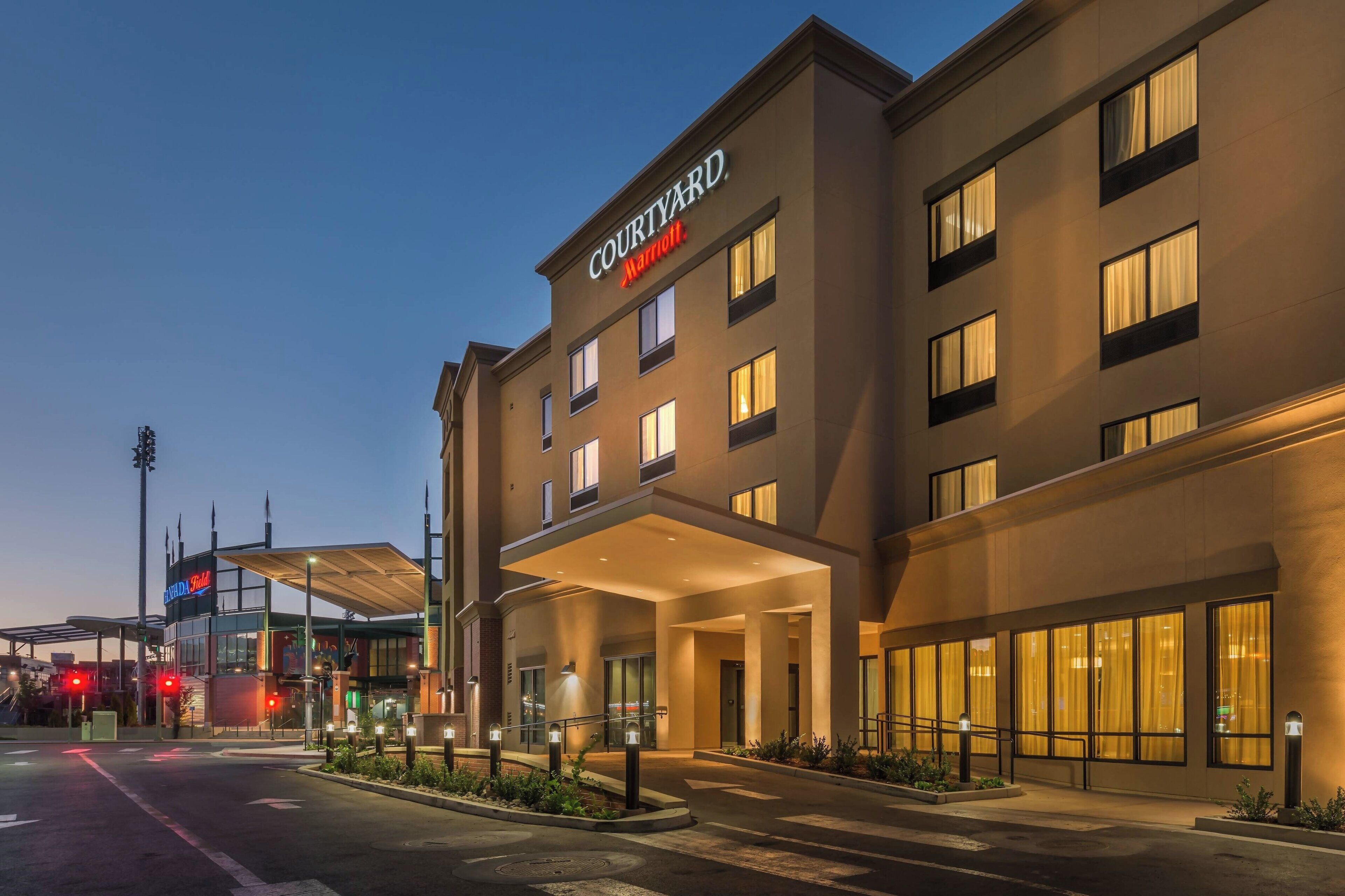 Um hotel Courtyard Marriott com fachada moderna, grandes janelas e área de entrada coberta.
