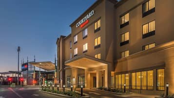 Um hotel Courtyard Marriott com fachada moderna, grandes janelas e área de entrada coberta.