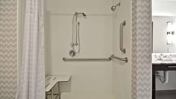 A shower with grab bars, a white sink, and a mirror.