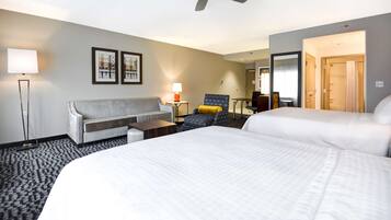 Habitación de hotel con una cama grande, un sofá, una silla, un escritorio y un ventilador de techo.