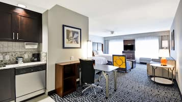 Una habitación de hotel compacta con kitchenette, una cama, una zona de estar y un televisor.