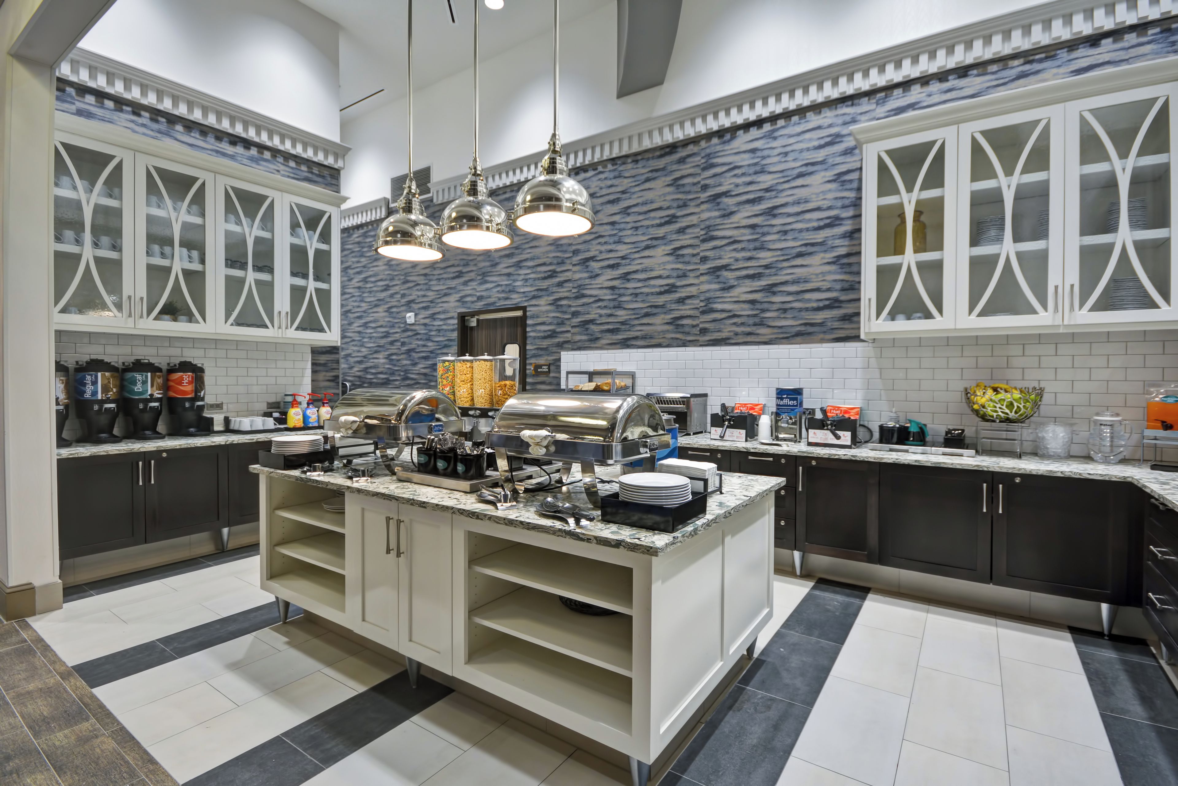 A modern kitchen with a central island, built-in appliances, and a patterned backsplash.