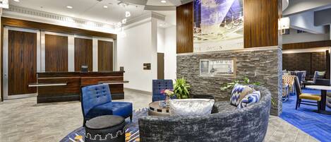A hotel lobby with a reception desk, seating area, and a stone accent wall.