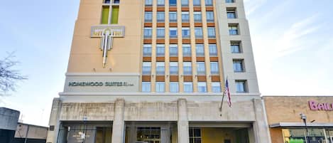 Un hotel con fachada color beige, varios pisos y un letrero que dice 'Homewood Suites'.