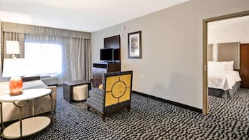 A hotel room with a bed, a desk with a chair, a television, and a lamp.