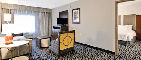 A hotel room with a bed, a desk with a chair, a television, and a lamp.