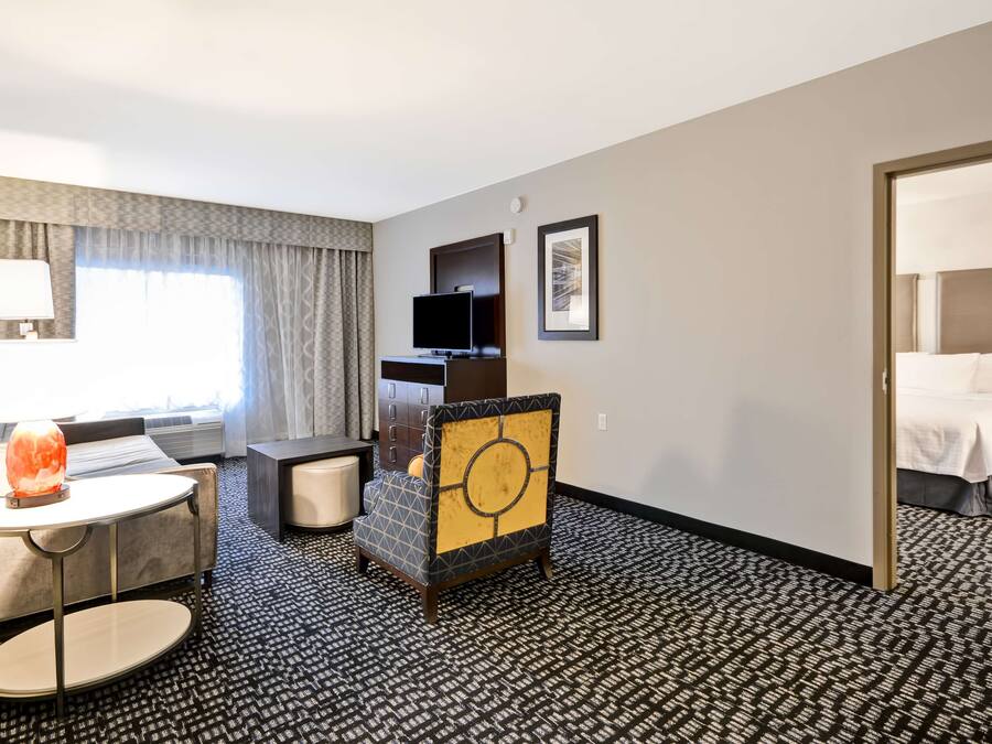 A hotel room with a bed, a desk with a chair, a television, and a lamp.