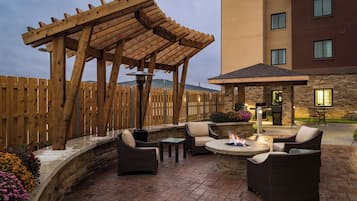 An outdoor patio area with a pergola, seating, and a fire feature.