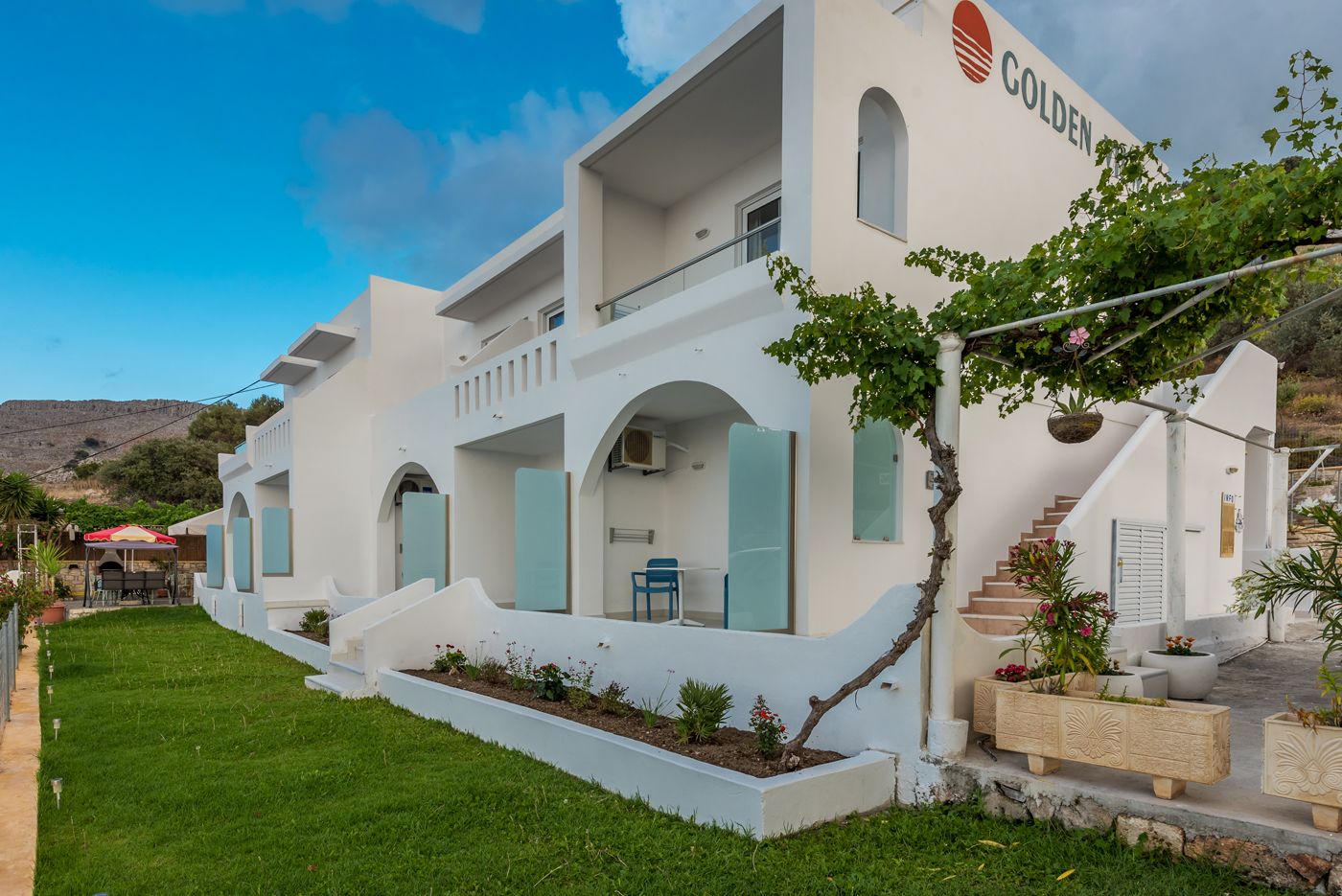 A white building with a balcony and a sign that reads "GOLDEN".