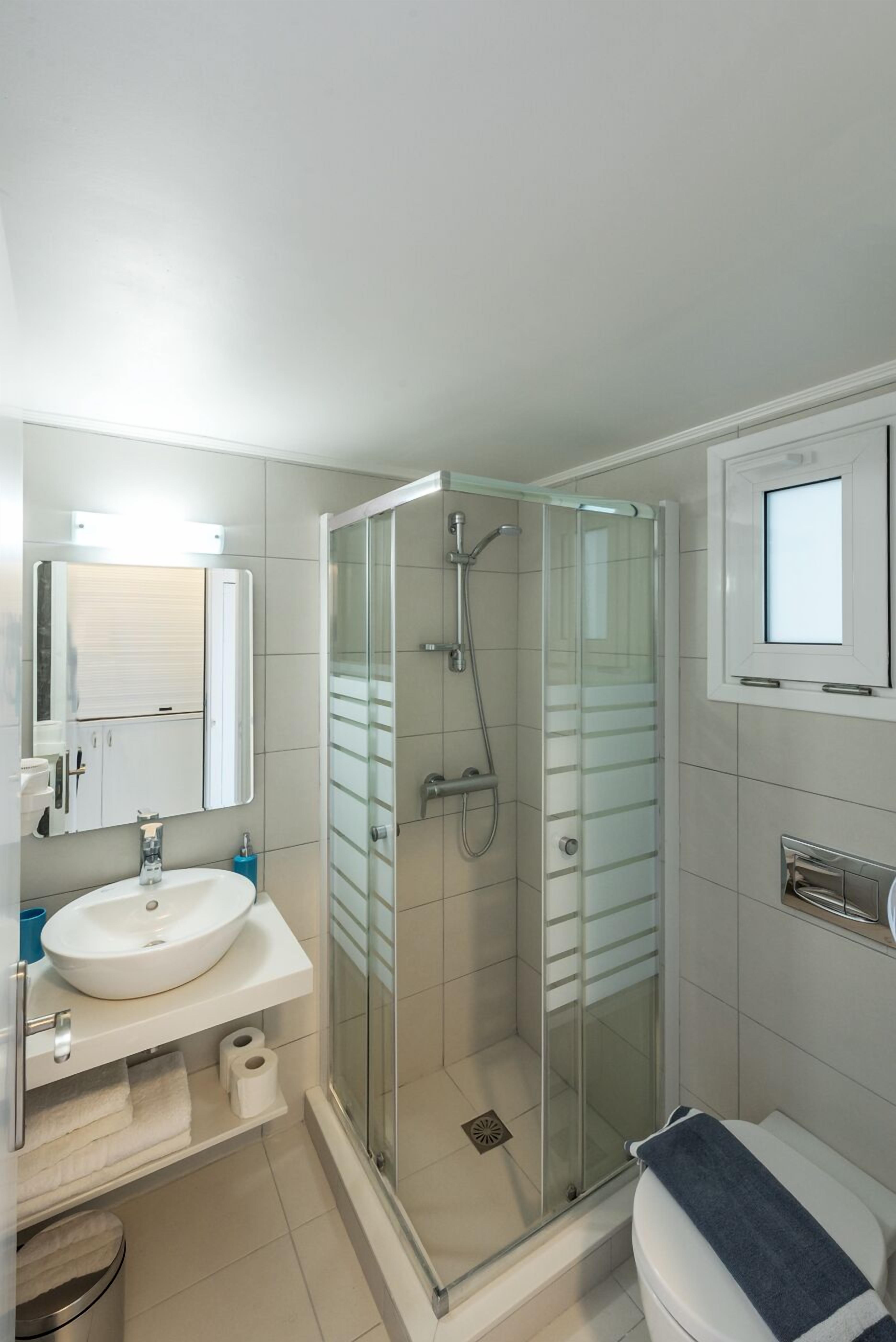 A modern bathroom with a glass-enclosed shower, a white sink, and a toilet.