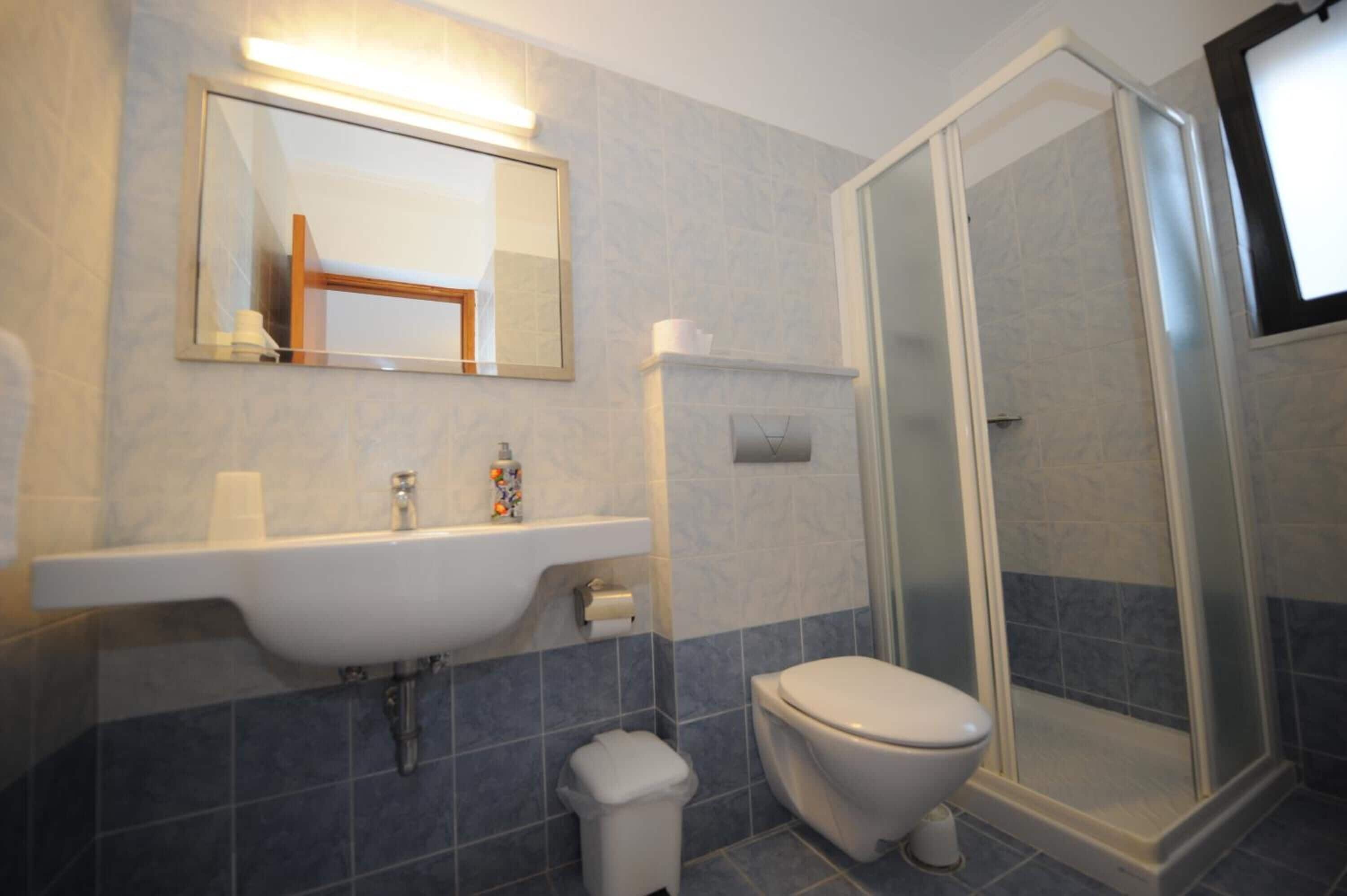 Une salle de bain équipée d’un lavabo, de toilettes et d’une douche à parois en verre.