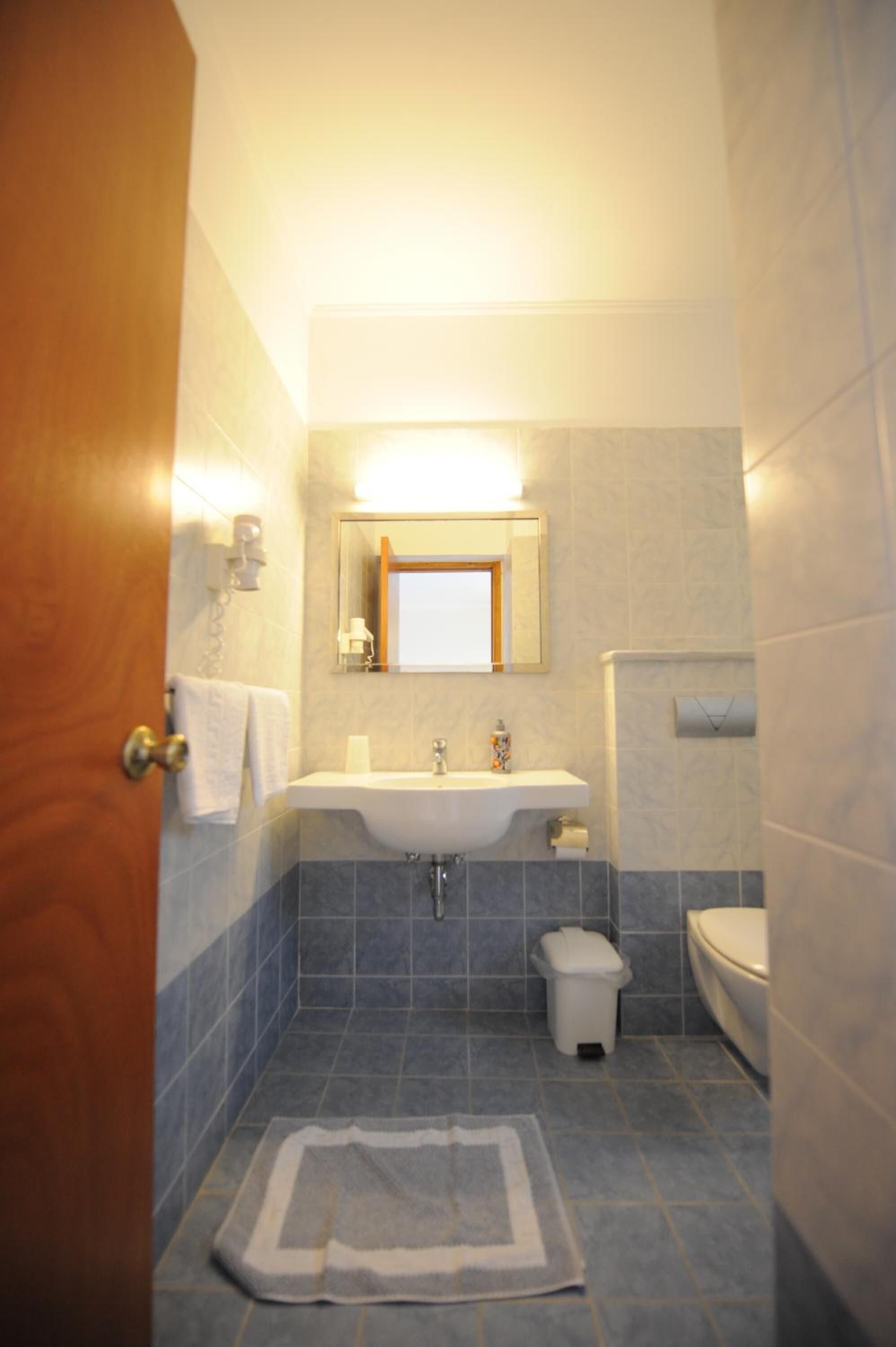Un baño con lavamanos, inodoro y espejo sobre el lavamanos.
