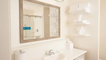 Un bagno con uno specchio grande, un lavandino e porta asciugamani.