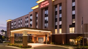 A Hampton Inn & Suites hotel with a modern facade, large windows, and a welcoming entrance.