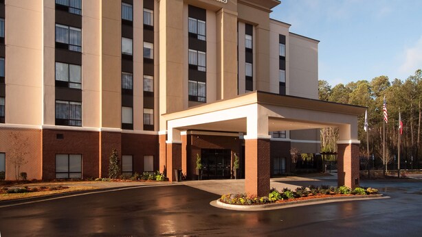 A Hampton Inn & Suites hotel with a covered entrance, brick facade, and multiple windows.
