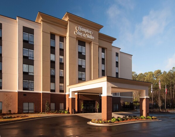 A Hampton Inn & Suites hotel with a covered entrance, brick facade, and multiple windows.