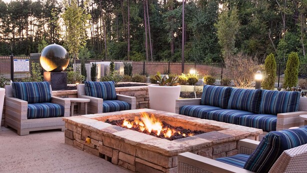 An outdoor seating area with a fire pit, wicker furniture, and a decorative sphere.