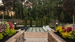 A garden with a chessboard, stone walls, and various plants.