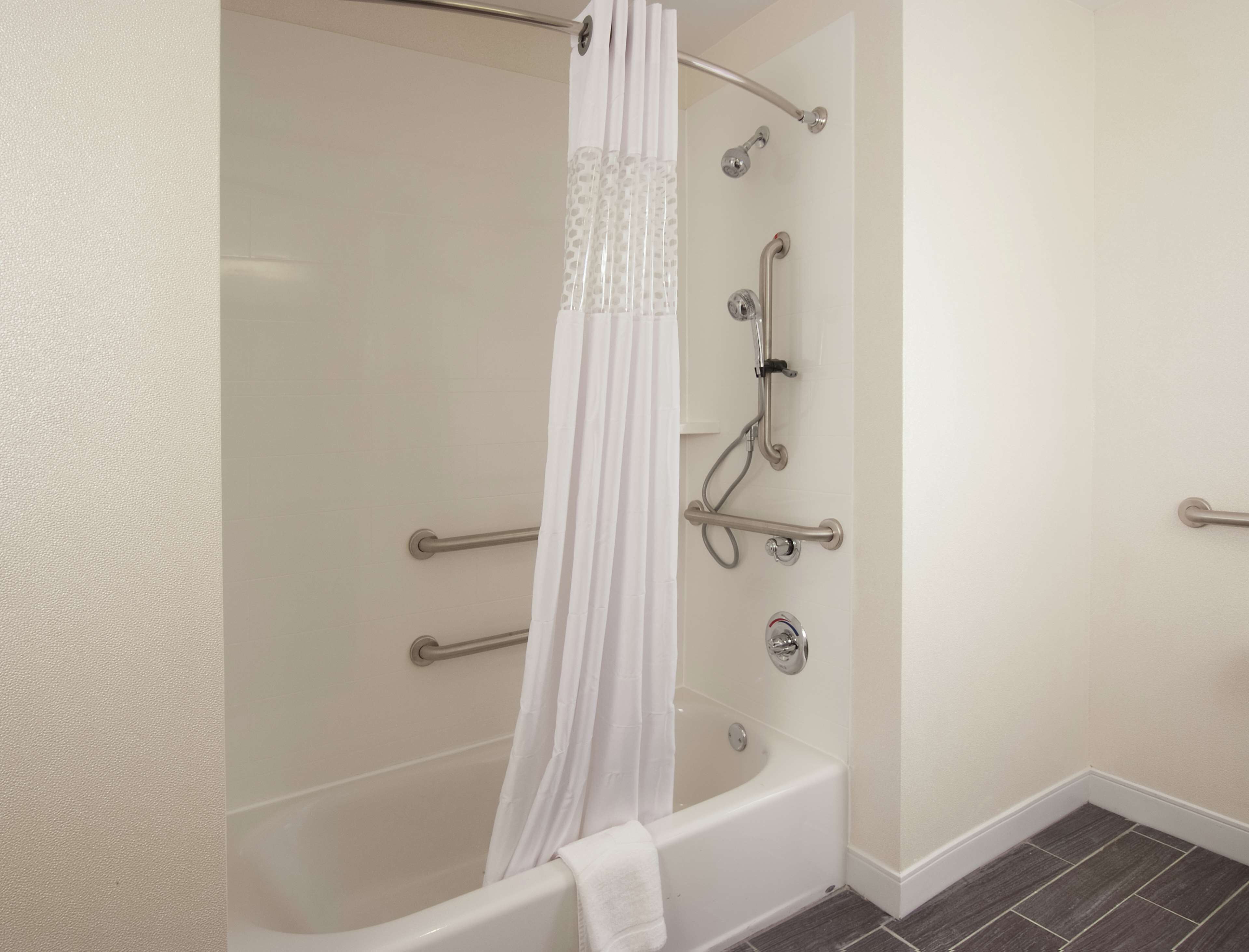 A modern bathroom with a walk-in shower, grab bars, and a bathtub.