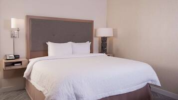 A neatly made bed with a large headboard, two bedside tables with lamps, and a telephone on one of the tables.
