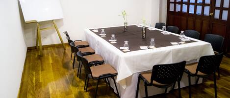 A conference room with a whiteboard, a long table with chairs, and a wooden floor.