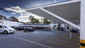A parking area with cars and a covered walkway. - Hotel Fernando Plaza (San Juan de Pasto)