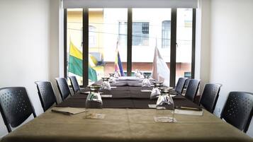 A conference room with a long table, chairs, and flags.
