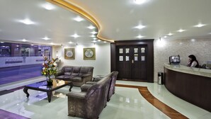 A hotel reception area with leather sofas, a reception desk, and a large window offering a view of the street. - Hotel Fernando Plaza (San Juan de Pasto)