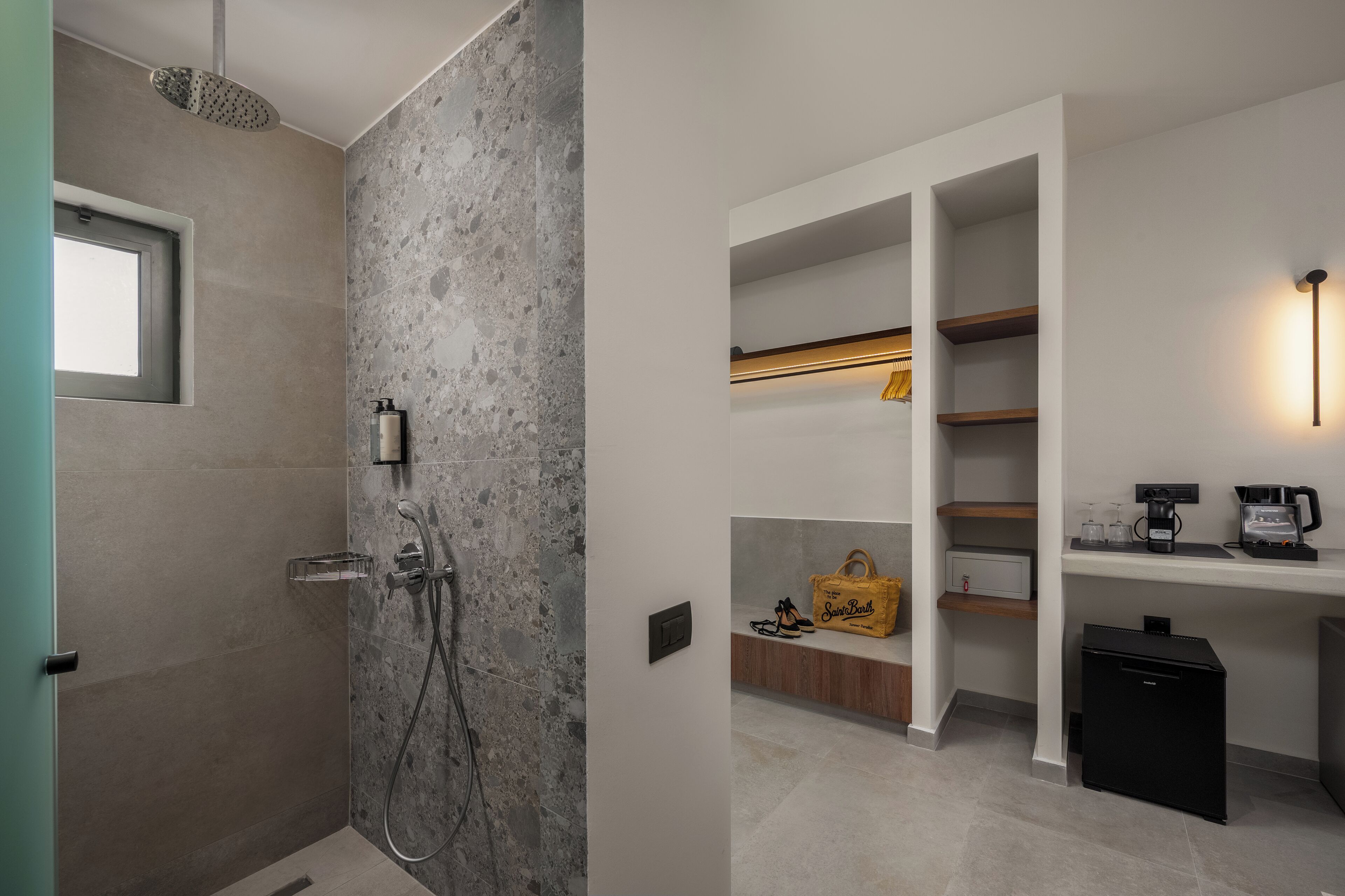 A modern bathroom with a shower, built-in shelves, and a coffee machine.