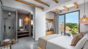 Un dormitorio moderno con una cama grande, un baño con puerta de cristal y vistas al exterior.
