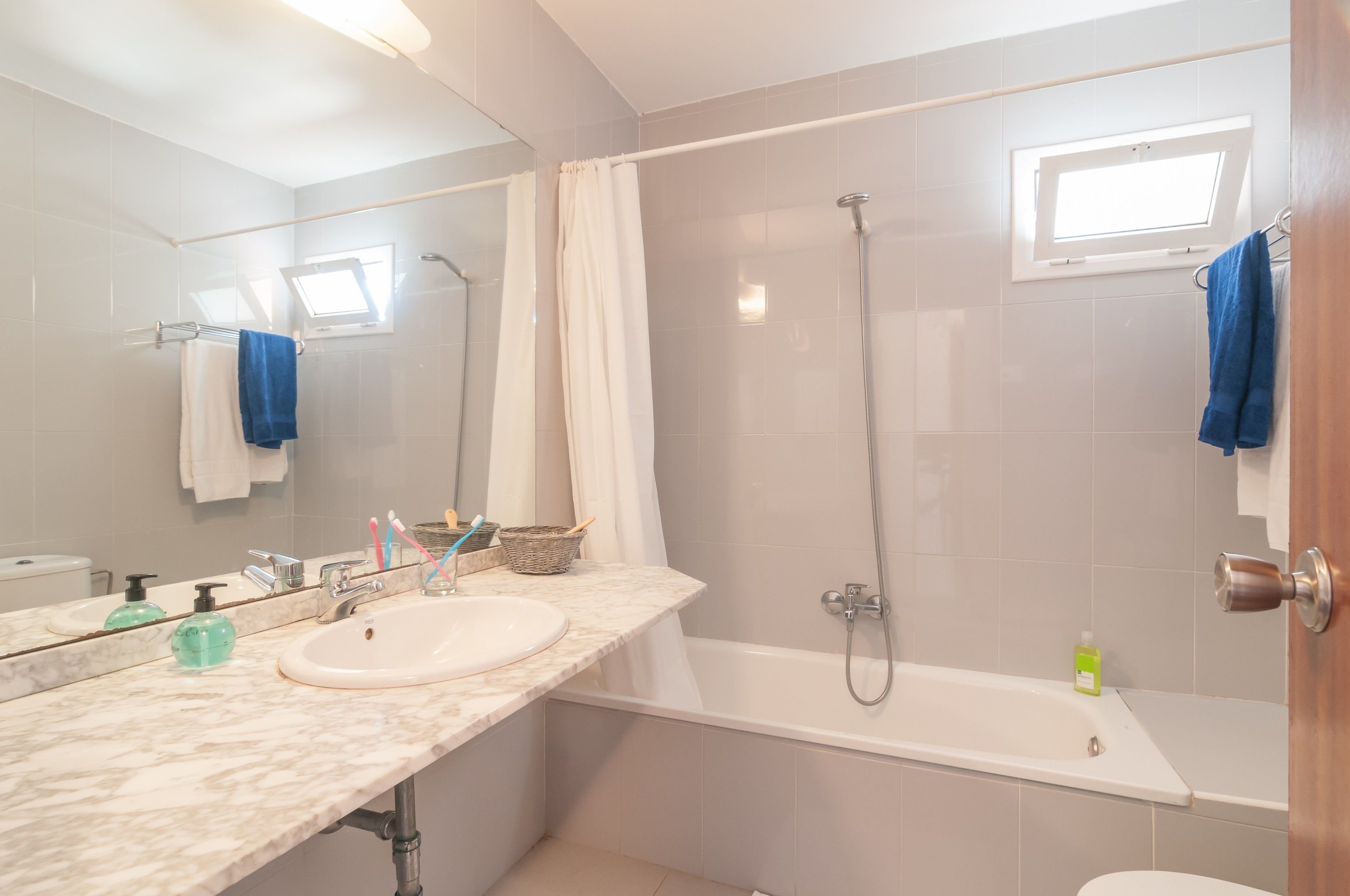 Un baño con lavamanos, espejo, ducha y ventana.