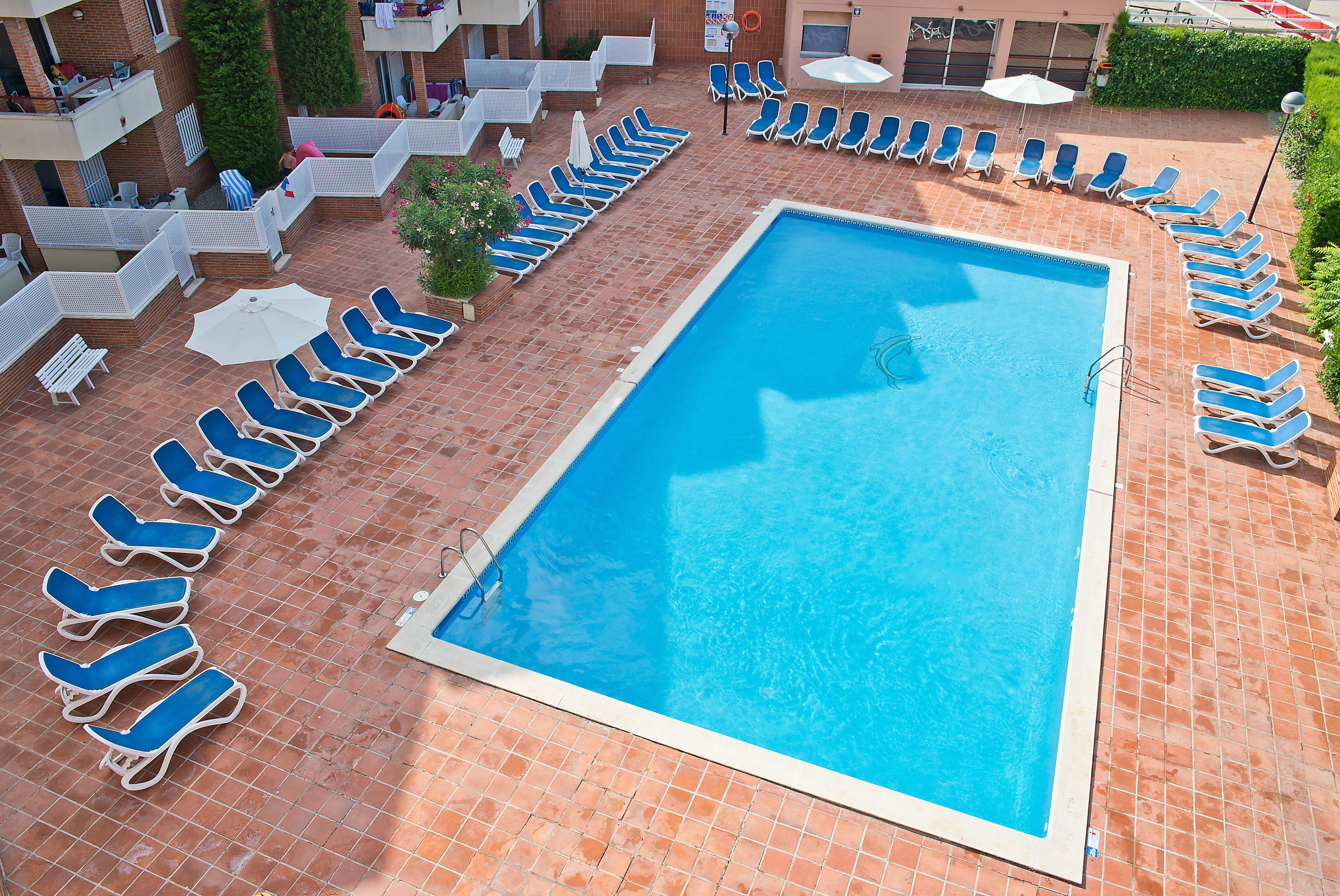 A swimming pool with blue lounge chairs arranged around it.