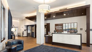En hotellobby med en receptionsdisk, en stor pelare och en sittgrupp med soffor.