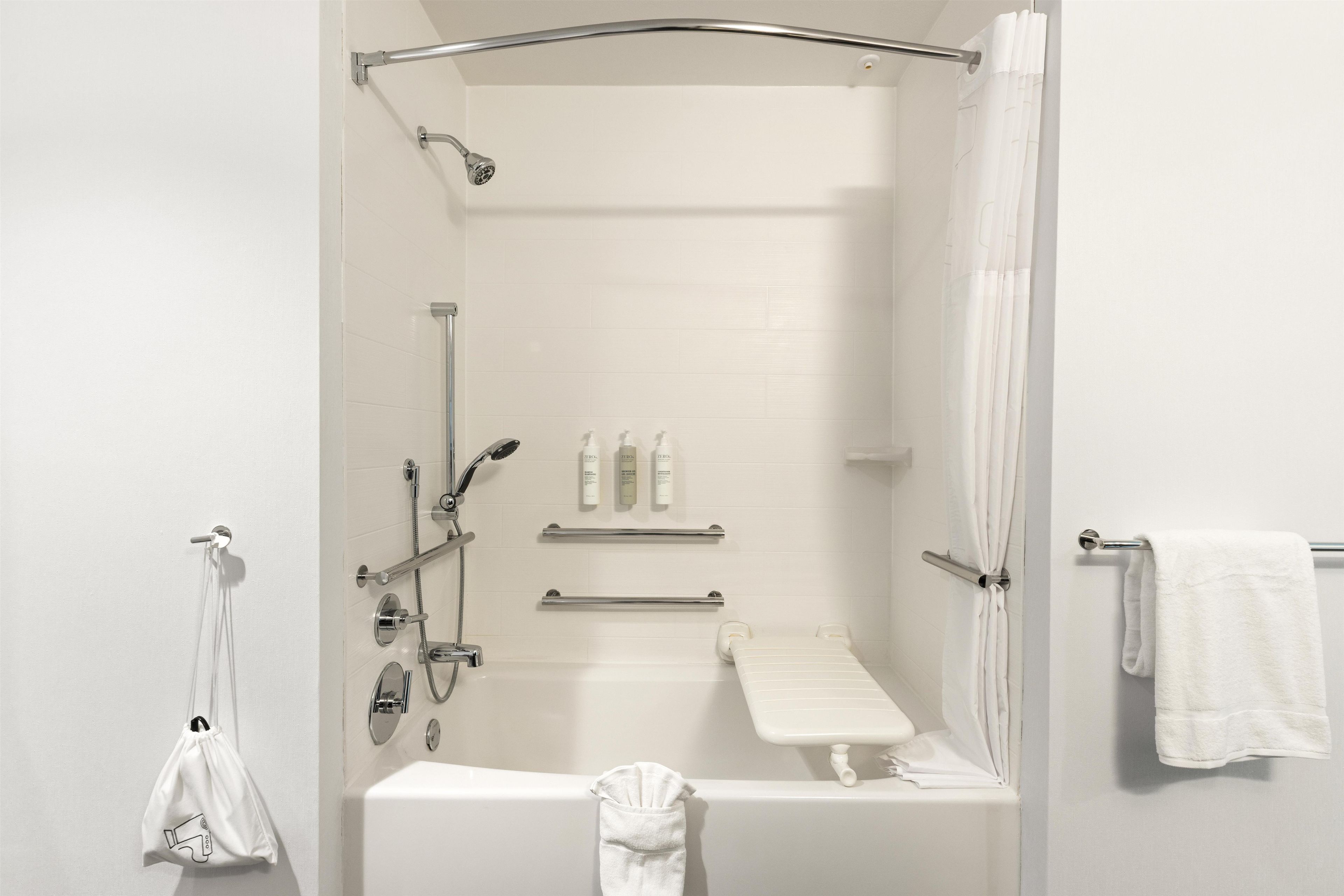 A bathroom with a shower, bathtub, towel rack, and a hanging bag.